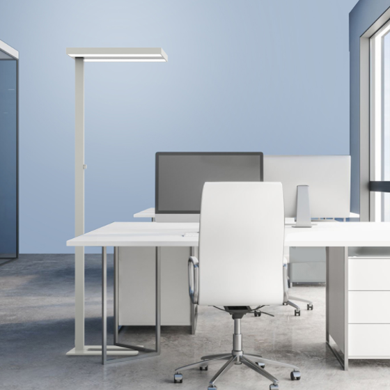 A white floor lamp beside a desk and office chair in a blue room
