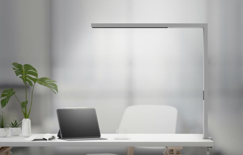A linear luminaire above a desk with a tablet and plants