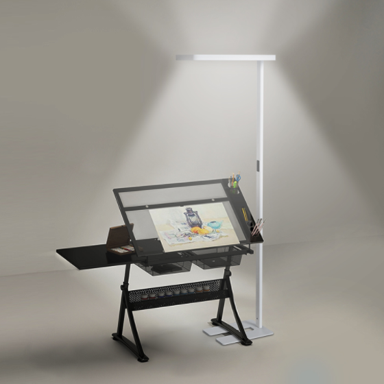 A white floor lamp beside an adjustable drawing workstation